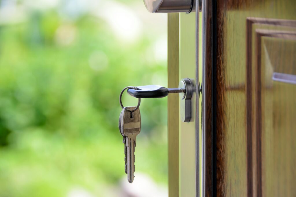 pexels-photo-101808-101808 Key inserted in door lock against a blurred green background, symbolizing security and real estate.