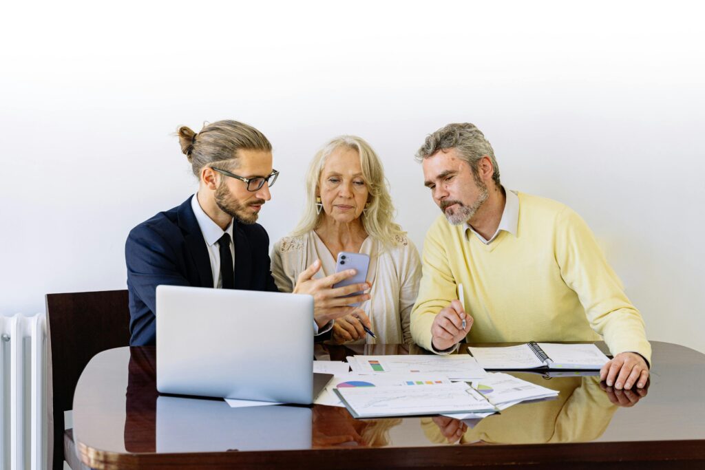 pexels-photo-5816286-5816286 Three individuals collaborating on financial documents during a business meeting.